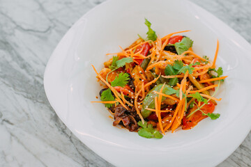 Vegetarian tomato, olives pepper salad in a white plate on a marble table, healthy food