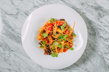 Vegetarian tomato, olives pepper salad in a white plate on a marble table, healthy food