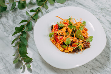 Vegetarian tomato, olives pepper salad in a white plate on a marble table, healthy food