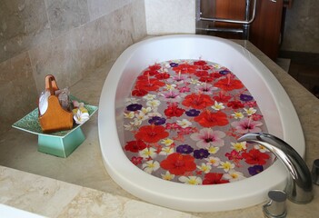 Close up of a white bathtub filled with hibiscus and plumeria flowers