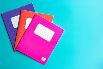 Office. Colored notebooks in purple, orange, pink colors on a turquoise background