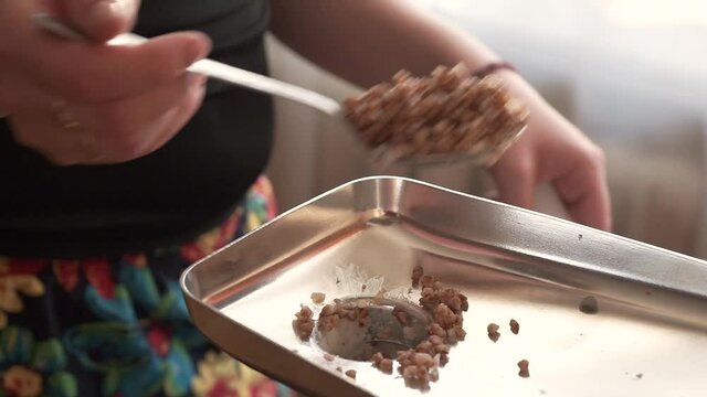 Cooking minced buckwheat with an electric meat grinder.A woman adds a tablespoon of minced meat to the meat grinder