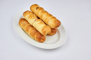 sausage in dough sprinkled with sesame seeds on a white background