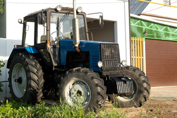A small-sized wheeled tractor stands near the house.