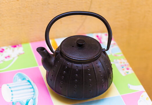 Black Chinese traditional teapot made of cast iron in the color of the tablecloth of the table