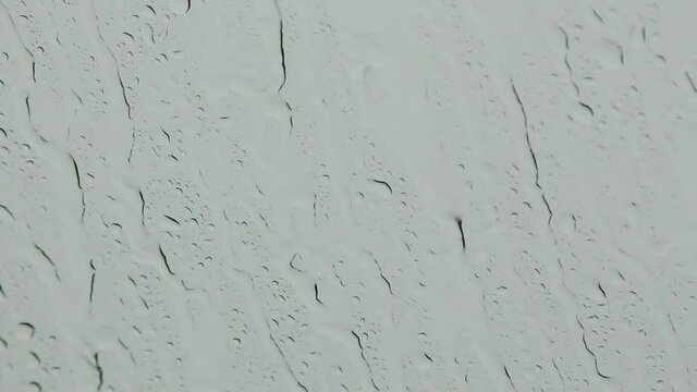 Raindrops on the windshield swipe by car swiper during heavy rain on traffic. 