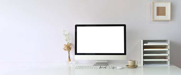 A comfortable workspace is surrounding by a white blank screen monitor and accessories.
