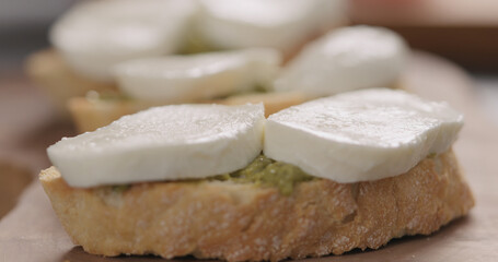 mozzarella slices on ciabatta slice with pesto on olive board