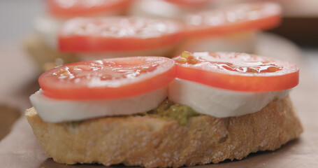 tomato on bruschetta with mozzarella and pesto on olive board