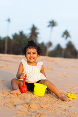 Playful Pretty Indian girl child/infant/toddler playing in the sand with her sand castle kit. Kid giving joyful expressions and playing on the beach.