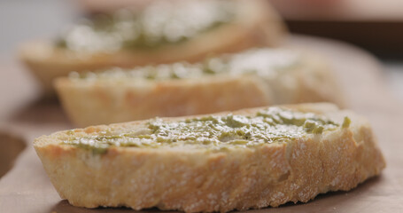 spread pesto on ciabatta slice on olive board