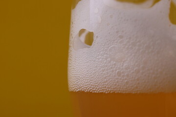 pub weise beer made of wheat with white foam in a glass  on the yellow background