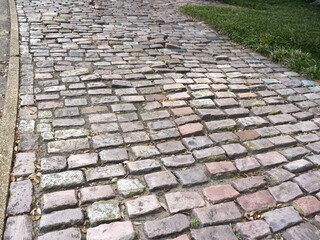 Uneven cobblestone pathway beside a grassy area