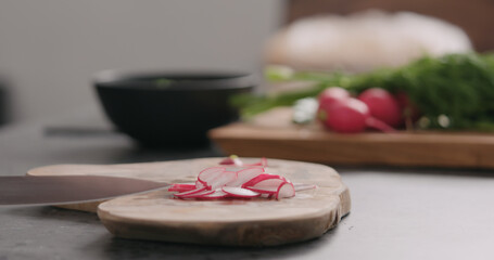 man slicing fresh radish on olive board side view