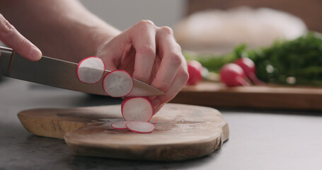 Obraz na płótnie Canvas man slicing fresh radish on olive board side view