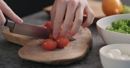 Man cutting cherry tomatoes on concrete countertop side view