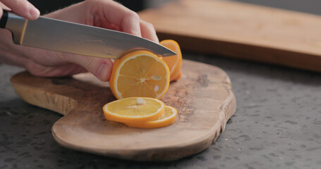 man slicing fresh orange lemon on olive board