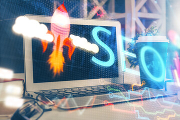 Double exposure of table with computer and seo drawing hologram. Search optimization concept.