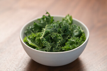 kale salad leaves in white bowl on walnut table