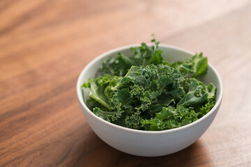kale salad leaves in white bowl on walnut table with copy space