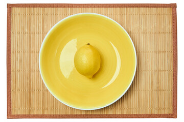 bright yellow lemon on a yellow plate on a cane place mat
