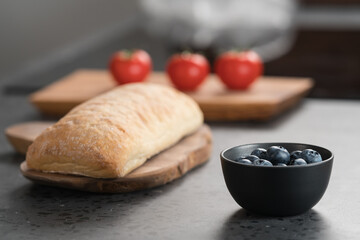 various food on concrete kitchen countertop like blueberries, ciabatta and tomatoes