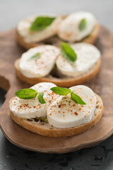 Bruschetta with mozzarella, basil and pesto on olive wood board