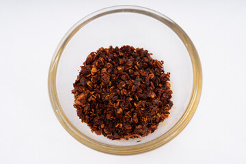 Chilli, red chilli flakes, dried chillies flakes in glass cup on a white background 