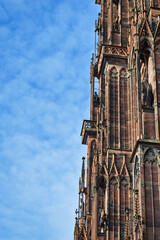 Part of tower of famous Strasbourg Cathedral in France in romanesque and gothic architecture style in front of blue sky