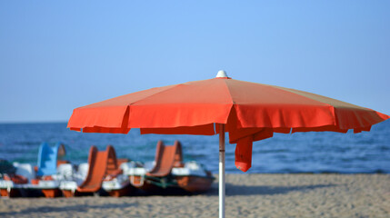 a red beach umbrella in front of the sea
