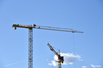 Tower cranes working at construction site on blue sky background