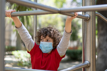 Fototapeta premium boy with a protective mask on playground. Coronavirus (COVID-19) lifestyle. Reopening of public park after quarantine lockdown.