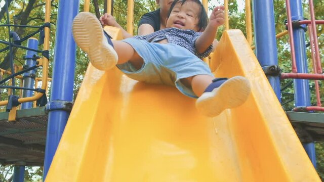 Asian toddler boy smile to play slider colorful playground in city park