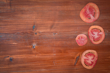 Background with chopped pieces of tomatoes lying on an old wooden table. Empty space for text on the left.