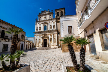 Fototapeta na wymiar The old church of St. Anna, Mesagne. Puglia, Italy under the clear blue sky of a sunny summer day, travel photography, street view with few beautiful decorative palm trees in foreground