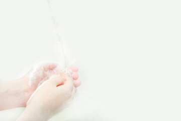 Fototapeta premium Closeup of female hands with freckles that are washed under running water
