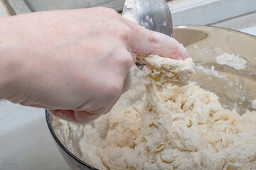 Thick dough is manually mixed in a transparent bowl.