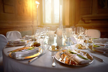 Metal plates with napkins and flowers in a restaurant on the background of glasses and windows