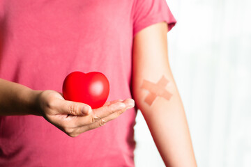 Red heart with a croos plaster on  arm. Blood donation concept