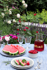 Tischdekoration mit Wassermelone und Himbeeren im Sommergarten
