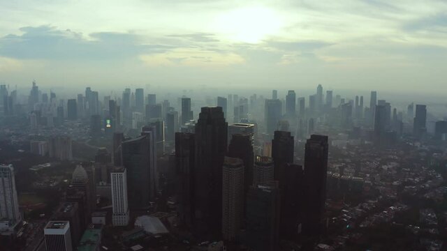 JAKARTA - Indonesia. June 04, 2020: Beautiful aerial scenery of Jakarta city at sunrise time with silhouette of skyscrapers. Shot in 4k resolution from drone flying forwards