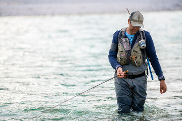 Close up of a fly fisherman wading in the river 