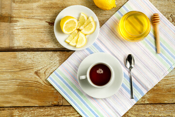White cup with tea with lemon and honey on a table on a napkin.