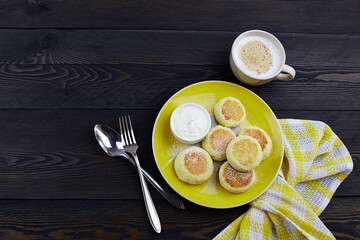 Cheesecakes (syrniki), curd fritters with with sour cream on wooden background, top view.