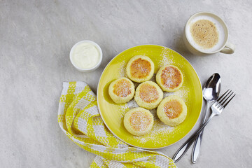 Cheesecakes (syrniki), curd fritters with with sour cream on light grey concrete background, top view.