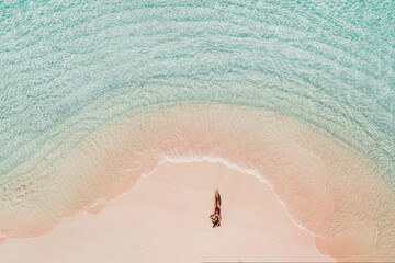 Woman in red swimsuit lying on famous pink beach in Komodo national park. Turquoise mint color clear water, tropical vacations. Drone aerial view from above. - 355846936