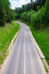 Asphalt road through summer green forest