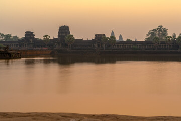 Fototapeta na wymiar Sunrise view of popular tourist attraction ancient temple complex Angkor Wat with reflected in lake Siem Reap, Cambodia