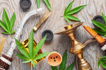 Hookah and cannabis leaves on a wooden background. Top view. Flat lay