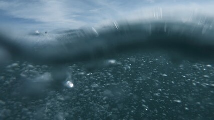 Wave on moving water surface close up in the middle of the screen.  Under Water Surface in the middle of the sea